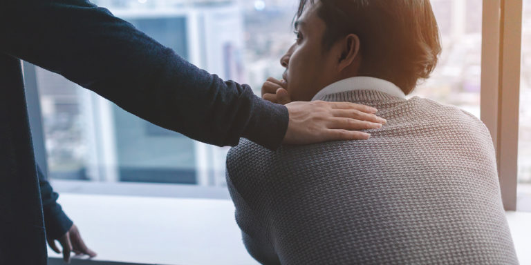 teenager with a supportive counsellor's hand on back.