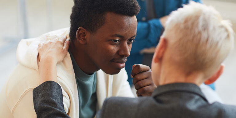 High angle view at young African-American man smiling gratefully to psychologist while while in support group circle