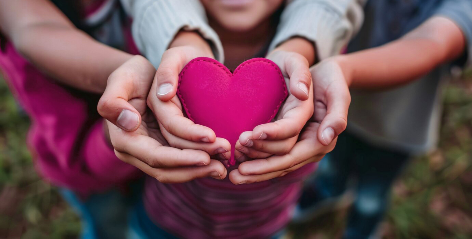 People, including a child, holding a fabric heart.