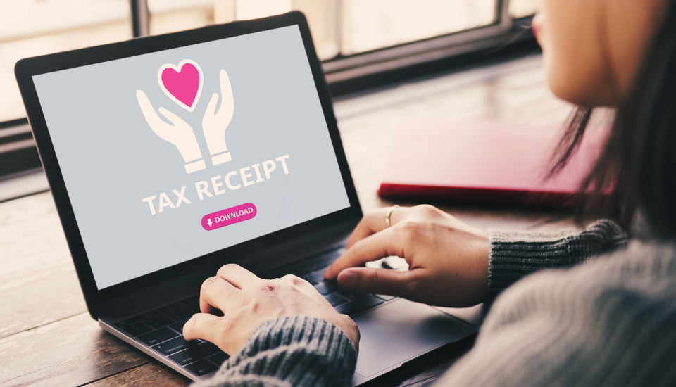A woman using a laptop displaying a tax receipt download button and a graphic symbolizing charitable giving.