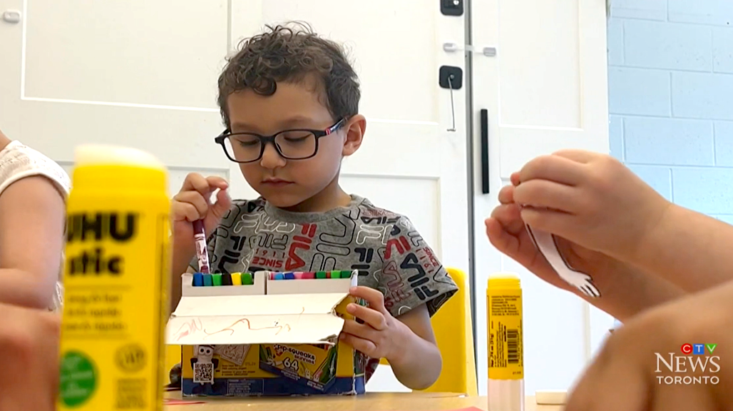 A child wearing glasses holding markers in a classroom, featured in a CTV News Toronto segment.