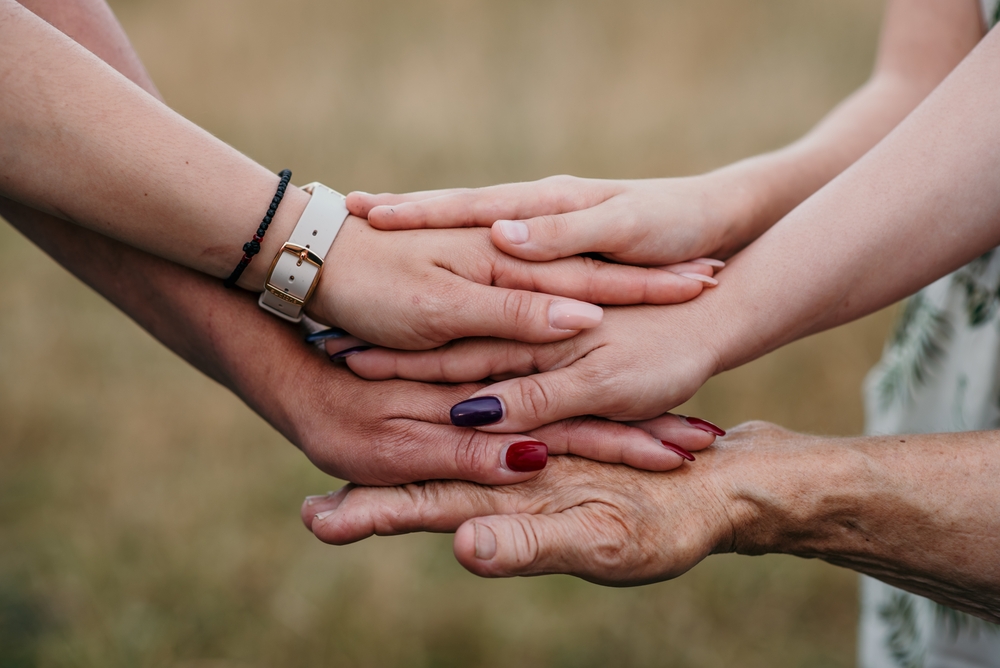 Women's hands from difference generations stacked together to represent unity and connection.