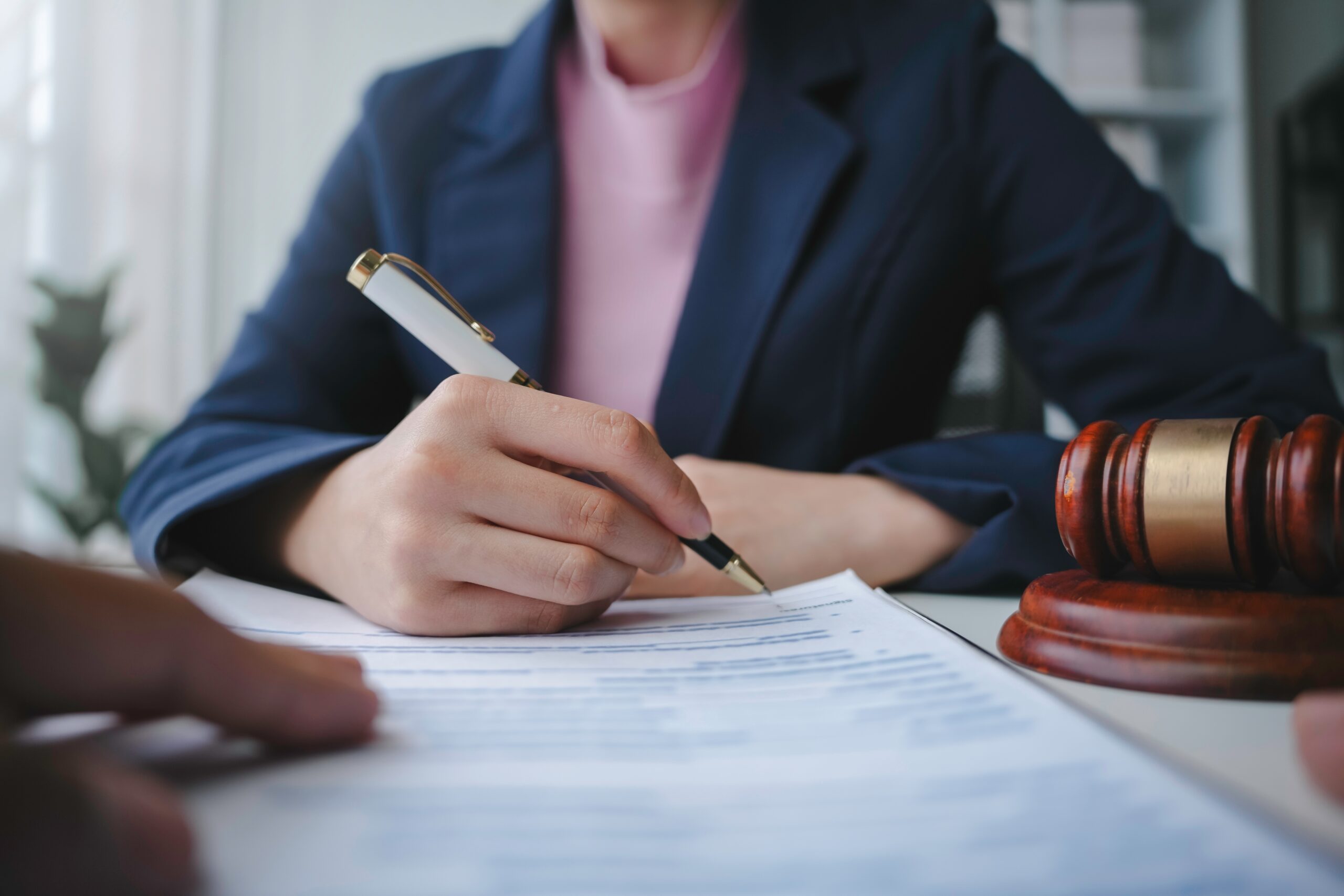 A woman holding a pen while completing paperwork at a table.